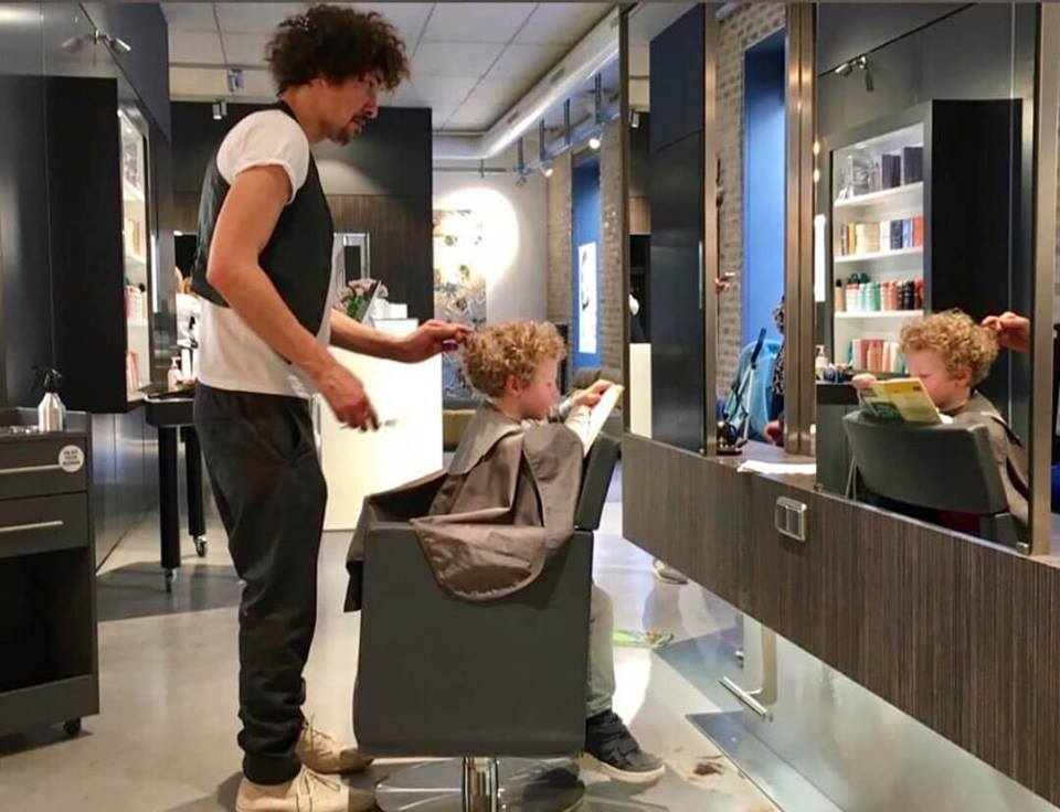 Foto - Danny Beuerbach schneidet in einem Salon einem lesenden Kind die Haare