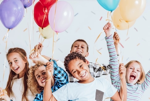 Kinderbuchlesen.de - Specials, Aktionen und Gewinnspiele: Abgebildet sind diverse Kinder mit Luftballons in der Hand und drumehrum fliegt Konfetti.